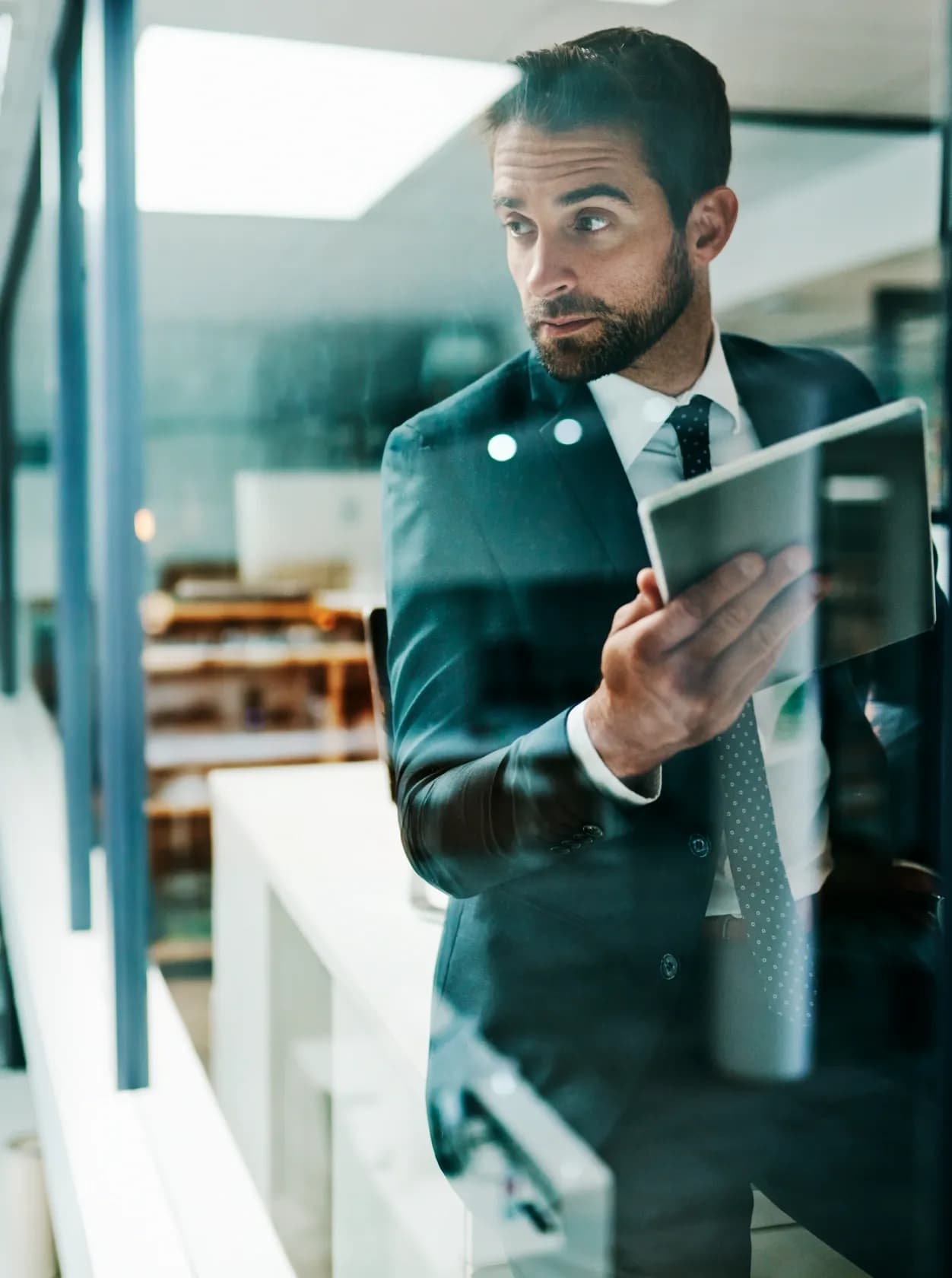 A man holding a tablet walking through a modern office